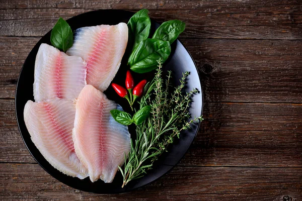 Frisches rohes Tilapia-Filet mit Thymian, Rosmarin, Basilikum und Chilipfeffer. Ansicht von oben. Kopierraum. — Stockfoto