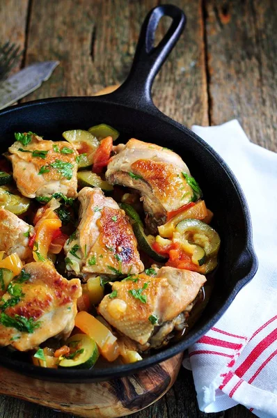 Stukjes kip gebakken met groenten - courgette, paprika, uien, tomaat, knoflook en peterselie. — Stockfoto