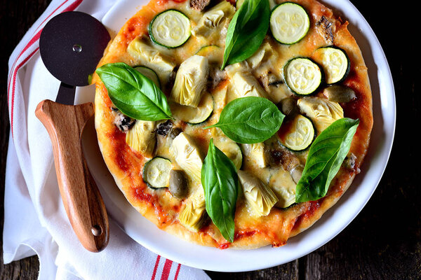Healthy vegetarian pizza made from corn flour with artichokes, zucchini, mozzarella, blue cheese, capers berries and organic basil. Healthy food.