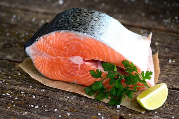 Шматок свіжого сирого лосося з органічною петрушкою на старому дерев'яному фоні . — стокове фото