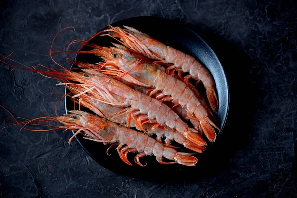 Gamberetto fresco crudo su piatto nero su fondo nero bruciato. Vista dall'alto — Foto Stock