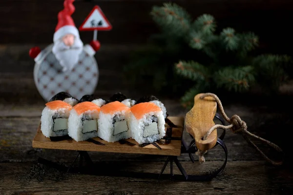 W domu sushi z łososiem na małe sanie, tło Boże Narodzenie — Zdjęcie stockowe