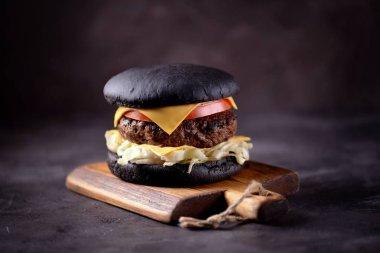 Sığır eti, buzdağı salatası, dilim domates ve kızarmış ekmek peynir ile sağlıklı siyah burger. Sağlıklı gıda.