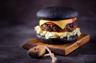 Sığır eti, buzdağı salatası, dilim domates ve kızarmış ekmek peynir ile sağlıklı siyah burger. Sağlıklı gıda.