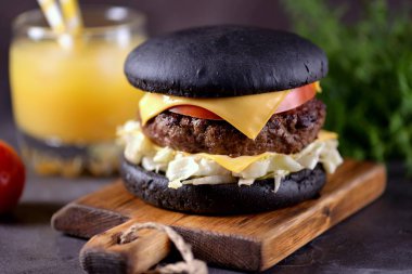 Sığır eti, buzdağı salatası, dilim domates ve kızarmış ekmek peynir ile sağlıklı siyah burger. Sağlıklı gıda.