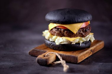 Sığır eti, buzdağı salatası, dilim domates ve kızarmış ekmek peynir ile sağlıklı siyah burger. Sağlıklı gıda.