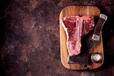 Taze çiğ t-bones biftek bir zeytin ahşap tahta deniz tuzu ile ve bir mutfak balta. Üstten Görünüm.