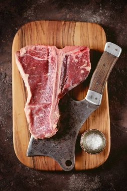 Taze çiğ t-bones biftek bir zeytin ahşap tahta deniz tuzu ile ve bir mutfak balta. Üstten Görünüm.