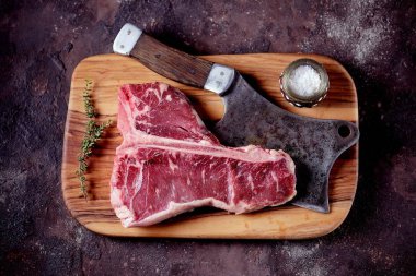 Taze çiğ t-bones biftek bir zeytin ahşap tahta deniz tuzu ile ve bir mutfak balta. Üstten Görünüm.