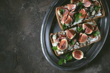 Sandviç ciabatta ekmek, yumuşak peynir, mavi peynir, jambon parma, incir ve balsamik krema. Üstte görüntü.