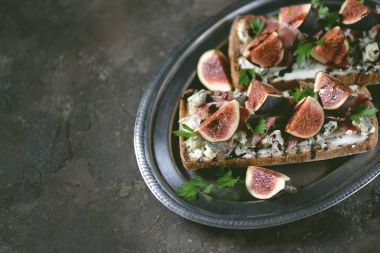 Sandviç ciabatta ekmek, yumuşak peynir, mavi peynir, jambon parma, incir ve balsamik krema. Üstte görüntü.