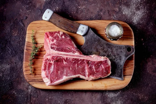 Taze çiğ t-bones biftek bir zeytin ahşap tahta deniz tuzu ile ve bir mutfak balta. Üstten Görünüm.