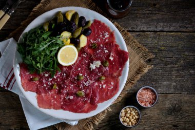 Dana carpaccio ile parmesan, roka, salatalık turşusu, kabak, Sele zeytin ve Kapari.