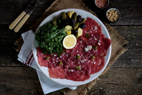 Rundercarpaccio Met Parmezaan Rucola Gepekelde Komkommers Squash Gedroogde Olijven Kappertjes — Stockfoto