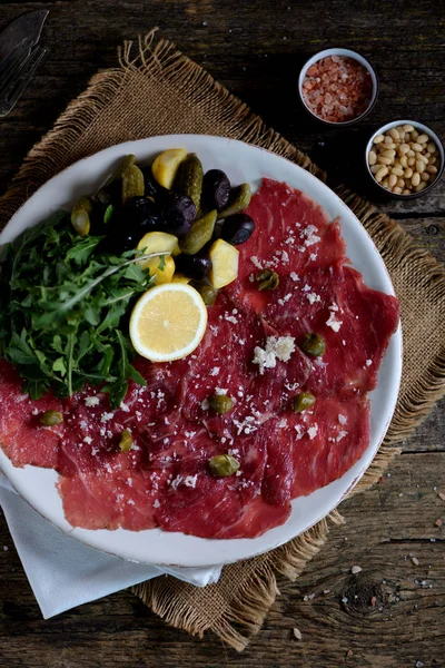 Beef Carpaccio Parmesan Arugula Pickled Cucumbers Squash Dried Olives Capers — Stock Photo, Image