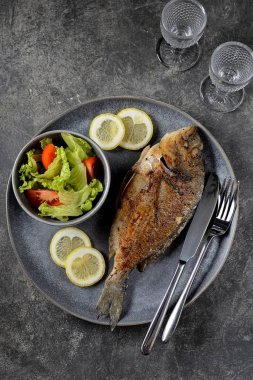 Limonlu ızgara dorado, marul ve domates. Sağlıklı yemek..