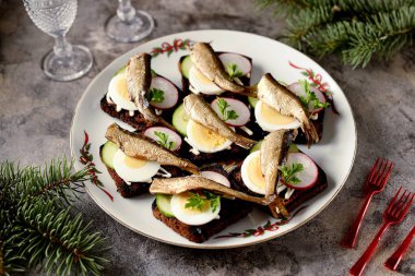 Çavdar ekmeği, salatalık, turp ve yumurtalı Baltık sprat sandviçleri. Noel arkaplanı.