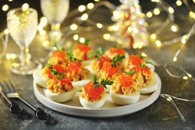 Stuffed eggs with salmon caviar. Christmas background.
