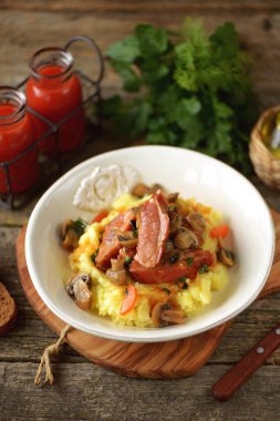 Mantar, soğan ve patates püresiyle servis edilen domates soslu havuçla pişirilmiş domuz pirzolası..