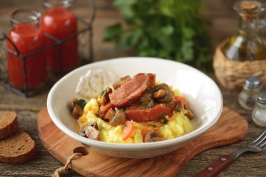 Mantar, soğan ve patates püresiyle servis edilen domates soslu havuçla pişirilmiş domuz pirzolası..