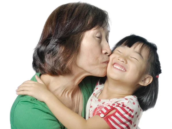 Азиатская бабушка целует щеку внучке — стоковое фото