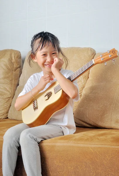 Asiática niña sostener un ukelele y sonriendo — Foto de Stock