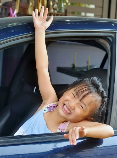 Little asian girl waving hand in a car — Stock Photo, Image