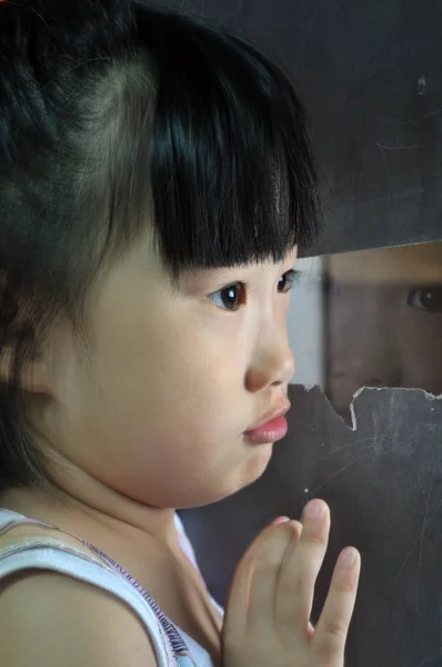 Szomorú, kicsi, ázsiai gyermek úgy néz ki az ablakba — Stock Fotó