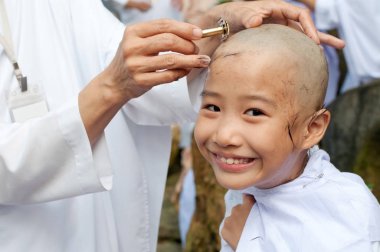 girl be removed hair to become a nun during a Buddhist ordinatio clipart