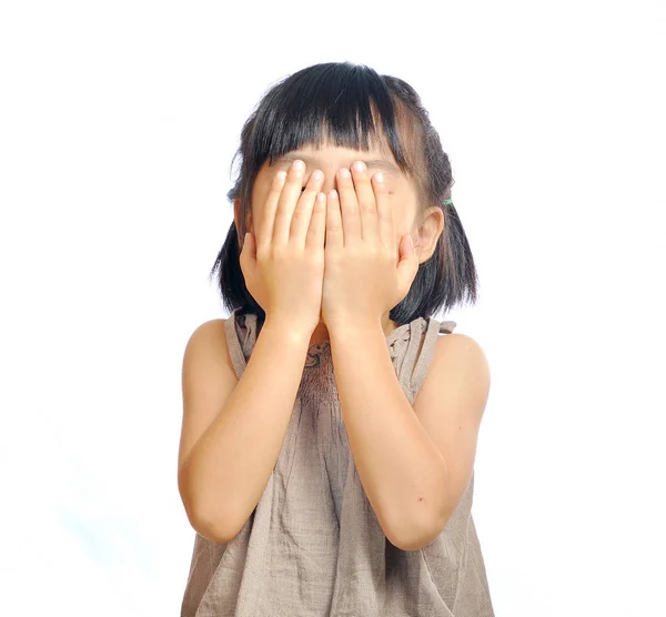 Азиатская маленькая девочка закрывает лицо рукой, изолированной в белом — стоковое фото