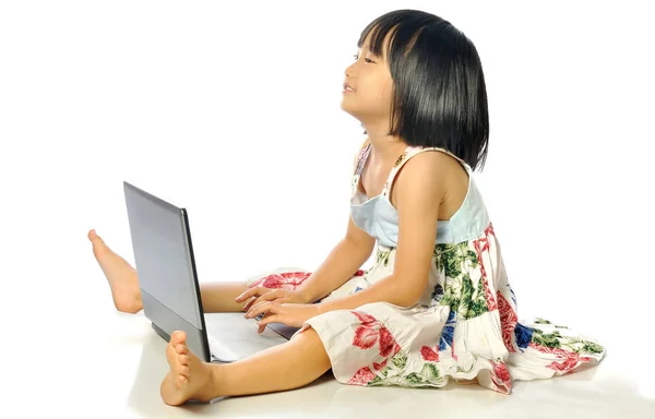 Kleines Mädchen auf dem Boden sitzend mit einem Laptop, weißer Hintergrund — Stockfoto