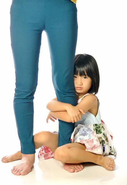 Asiatiska liten flicka kramar kvinnas ben och ledsen — Stockfoto