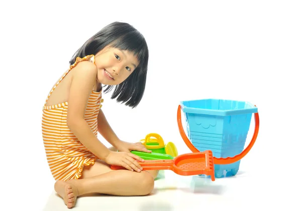 Азіатська маленька дівчинка в купальнику грає з пляжними іграшками — стокове фото