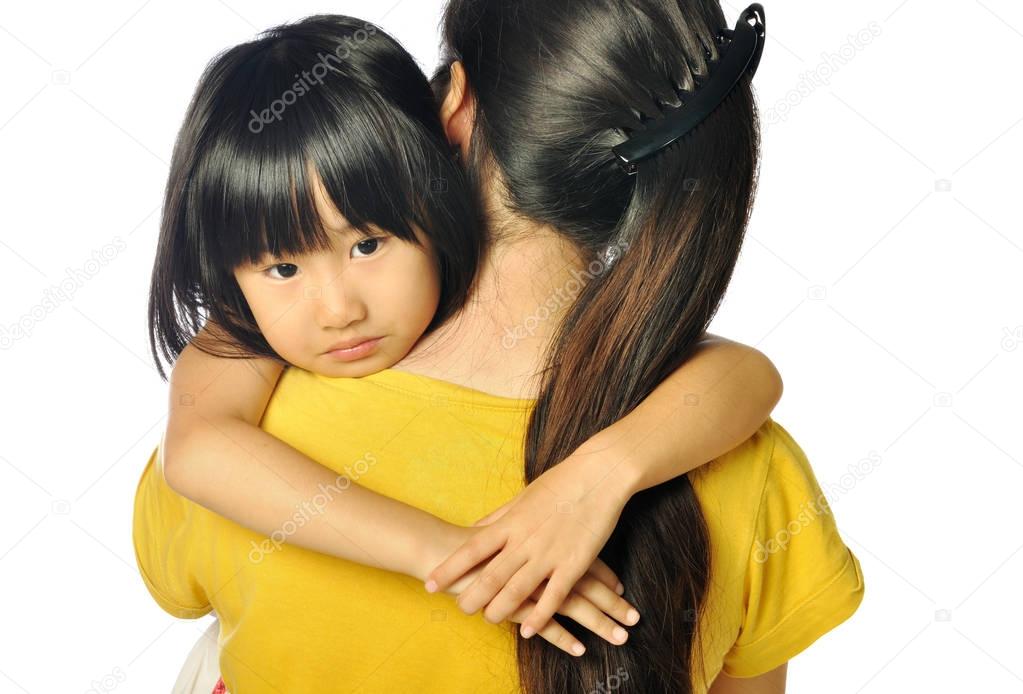 sad asian little girl hugging parent around shoulders