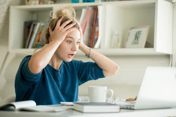 Portret van een aantrekkelijke vrouw aan tafel grijpend haar hoofd — Stockfoto