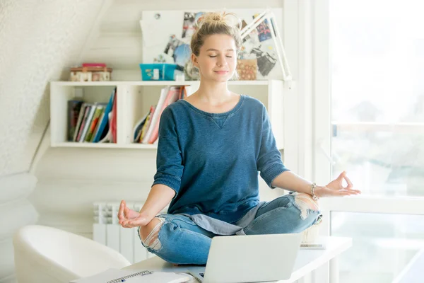 Porträt einer attraktiven Frau am Tisch, Lotuspose — Stockfoto