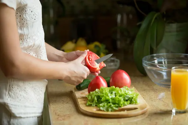 Händer skära tomater, sallad på bordet — Stockfoto