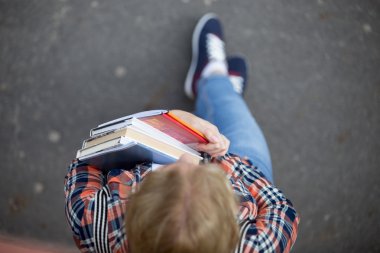 Bir yığın ders kitapları ve dizüstü bilgisayarlar ile öğrenci Bayan