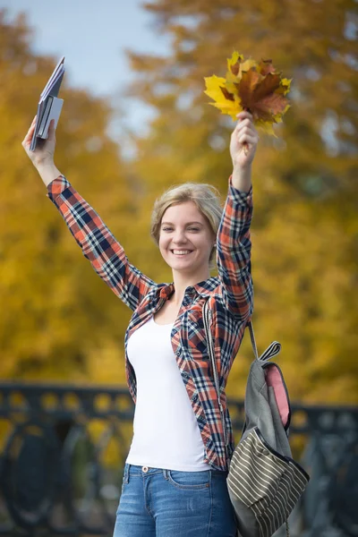 Portrait of smiling female young student outdoors holding yellow leaves — Stock Photo, Image