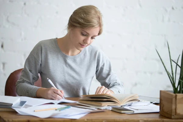 Student vrouwtje een schriftelijke taak uit te voeren in een beurt — Stockfoto