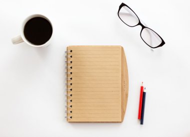 White office desk with a notebook and pencils, glasses