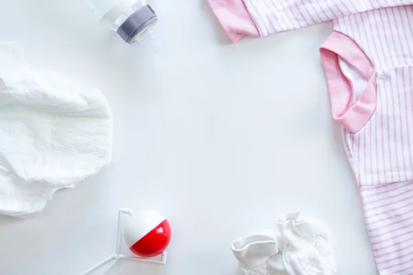 Set of baby supplies on table: diaper, beanbag, bottle, suit — Stock Photo, Image