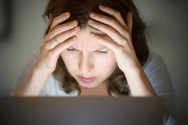 Porträt einer Frau, die spät in der Nacht am Laptop nach dem Kopf greift — Stockfoto