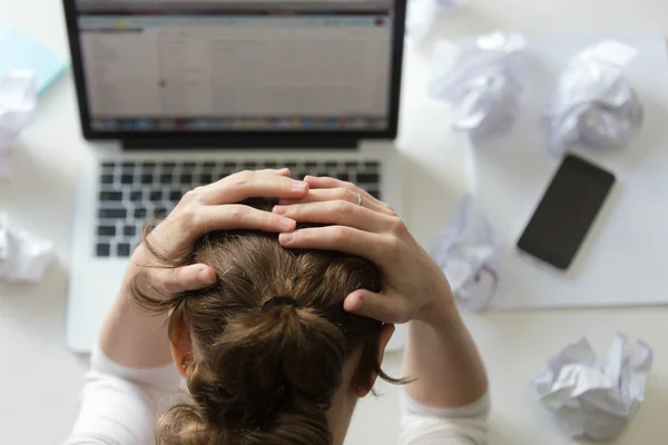 Retrato de uma mulher agarrando a cabeça na mesa perto do laptop — Fotografia de Stock