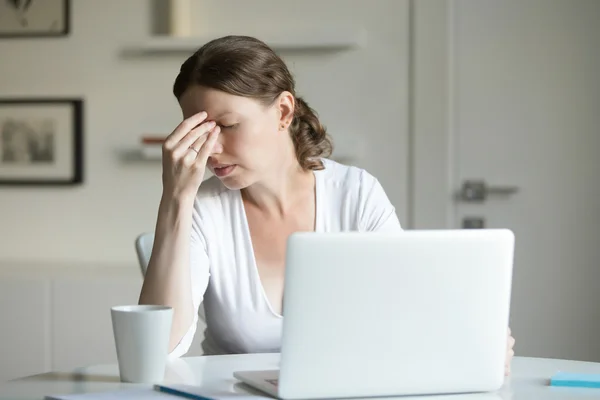 Retrato de uma mulher na mesa com laptop, mão na testa — Fotografia de Stock