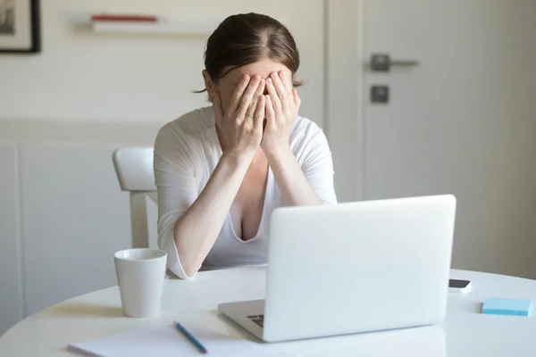 Retrato de mulher na mesa com laptop, as mãos fechando o rosto — Fotografia de Stock