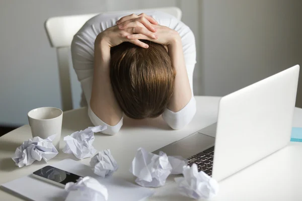 Retrato de uma mulher agarrando a cabeça perto do laptop — Fotografia de Stock