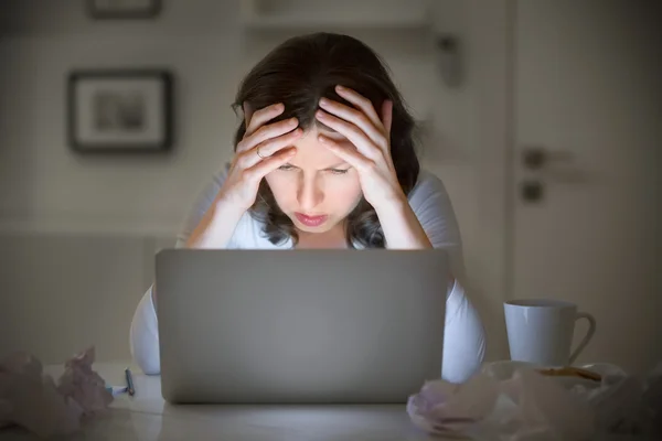 Retrato de uma mulher agarrando a cabeça perto do laptop — Fotografia de Stock