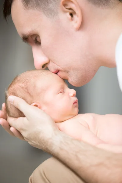 Young man kissing a newborn in his palms — Stock Photo, Image