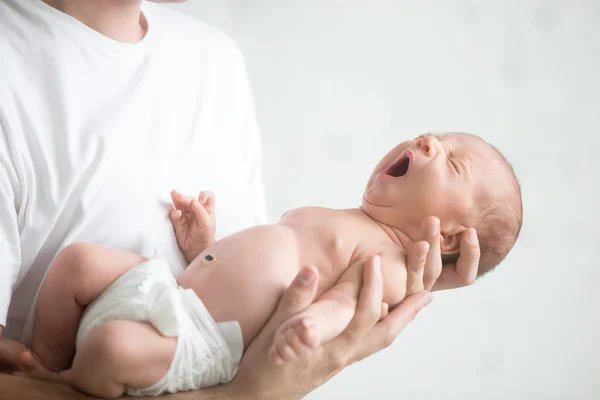 Male hands holding a screaming newborn — Stock Photo, Image